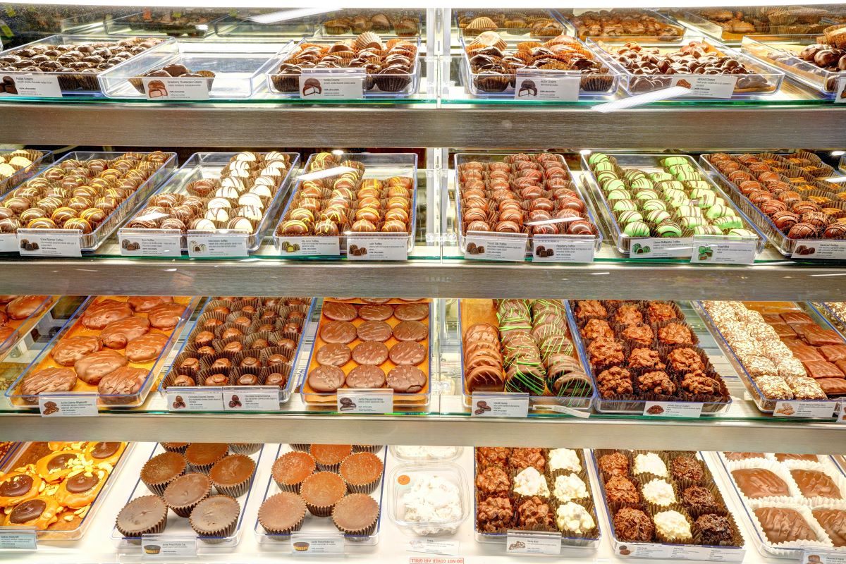 Chocolate Bar - case with trays - closeup - all kind of gourmet chocolate from large peanut butter cups, to truffles, turtles, and more.